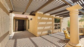 A covered patio area with a tiled floor, a column, and a door. - Golf, Swim & Grill: Snowbirds Escape in Sun Lakes (Chandler)