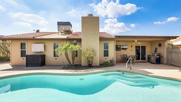 A residential property with a swimming pool, a covered patio, and a two-story house with a tiled roof. - Golf, Swim & Grill: Snowbirds Escape in Sun Lakes (Chandler)