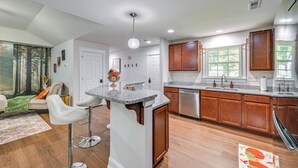 A modern kitchen with granite countertops, wooden cabinets, and a central island.