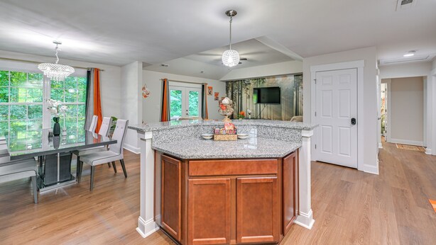 A spacious kitchen with a large island, wooden cabinets, and a dining area with a glass table and chairs.