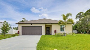 A single-story house with a garage, a well-maintained lawn, and a small tree. - Beach-hop & Golf! Port St Lucie Apt w/ Shared Yard (Port Saint Lucie)