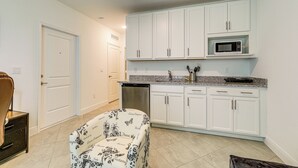 A kitchen with white cabinets, a microwave, and a built-in dishwasher. - Beach-hop & Golf! Port St Lucie Apt w/ Shared Yard (Port Saint Lucie)