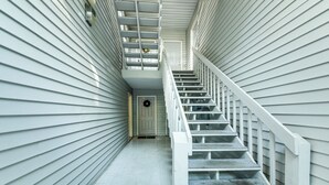 A narrow, enclosed stairwell with white railings and a door at the top. - 3 Mi to IU: Dog-friendly Condo w/ Pool Access! (Bloomington)