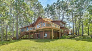 A large wooden house with multiple levels and balconies, surrounded by a forest. - Waterfront Escape on Big Sand Lake w/ Private Dock (Minong)