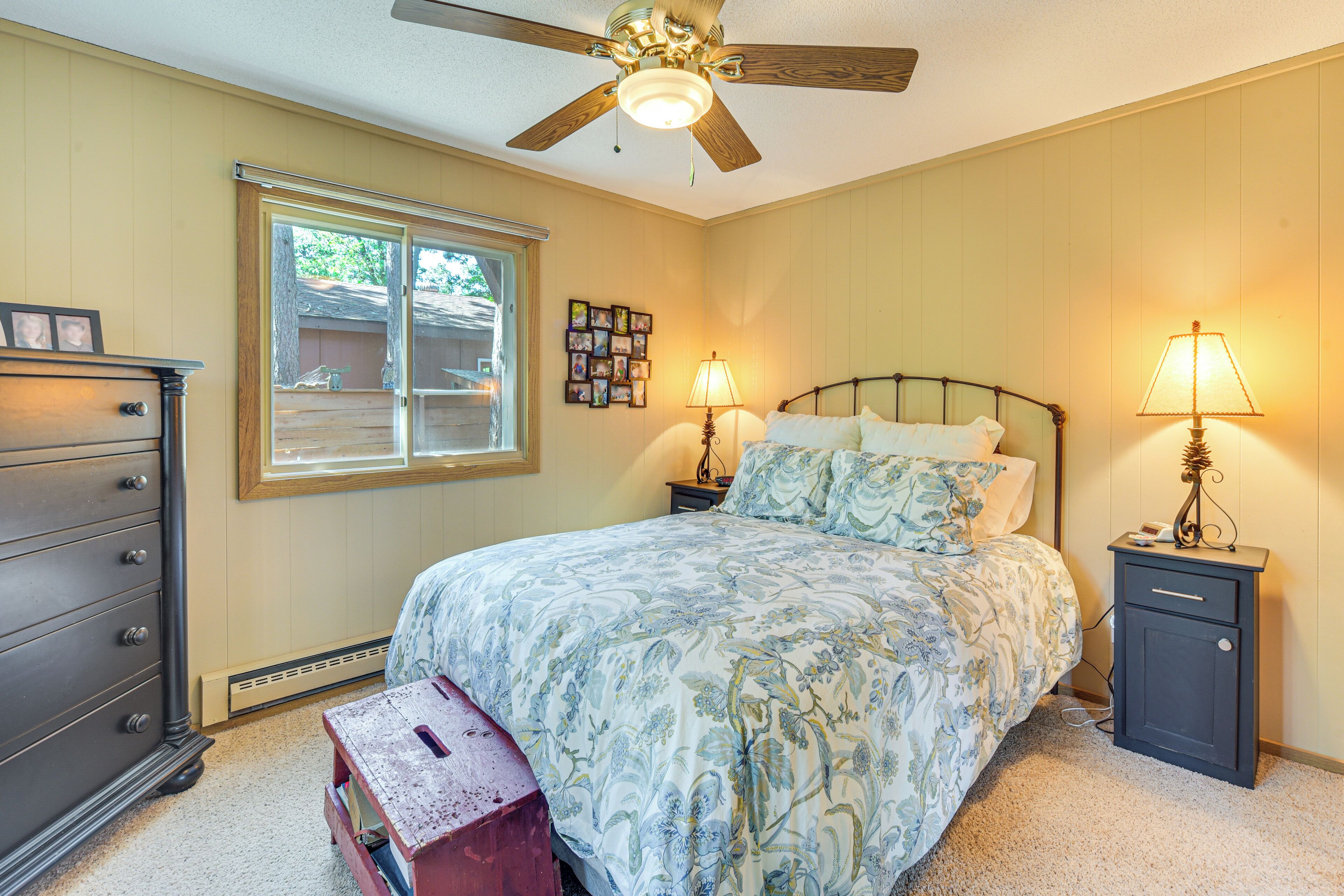A bedroom with a bed, nightstands, a dresser, a ceiling fan, and a window.