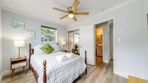 Una camera da letto con un letto in legno, una ventola a soffitto e un comodino con una lampada.