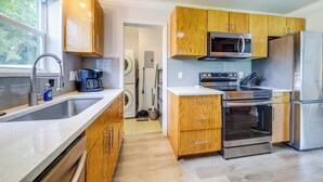 Una cucina moderna con mobili in legno, elettrodomestici in acciaio inossidabile, un'ampia finestra e un forno integrato.