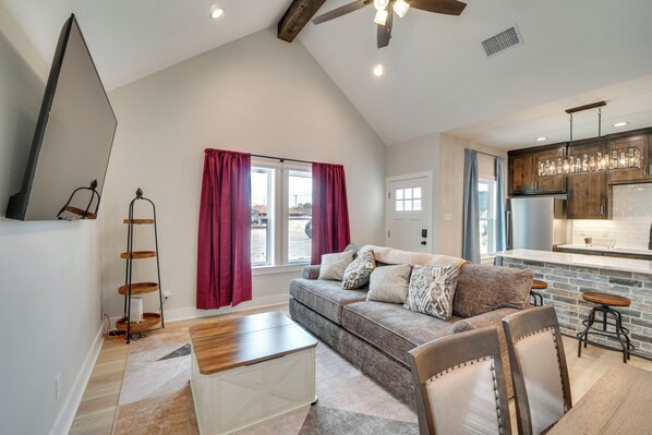 A spacious living room with a high ceiling, a sofa set, a coffee table, and a dining area with bar stools. - 7 Mi to Afb: Central & Modern San Angelo Home (San Angelo)