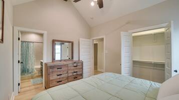 A bedroom with a bed, wooden dresser, and a walk-in closet.