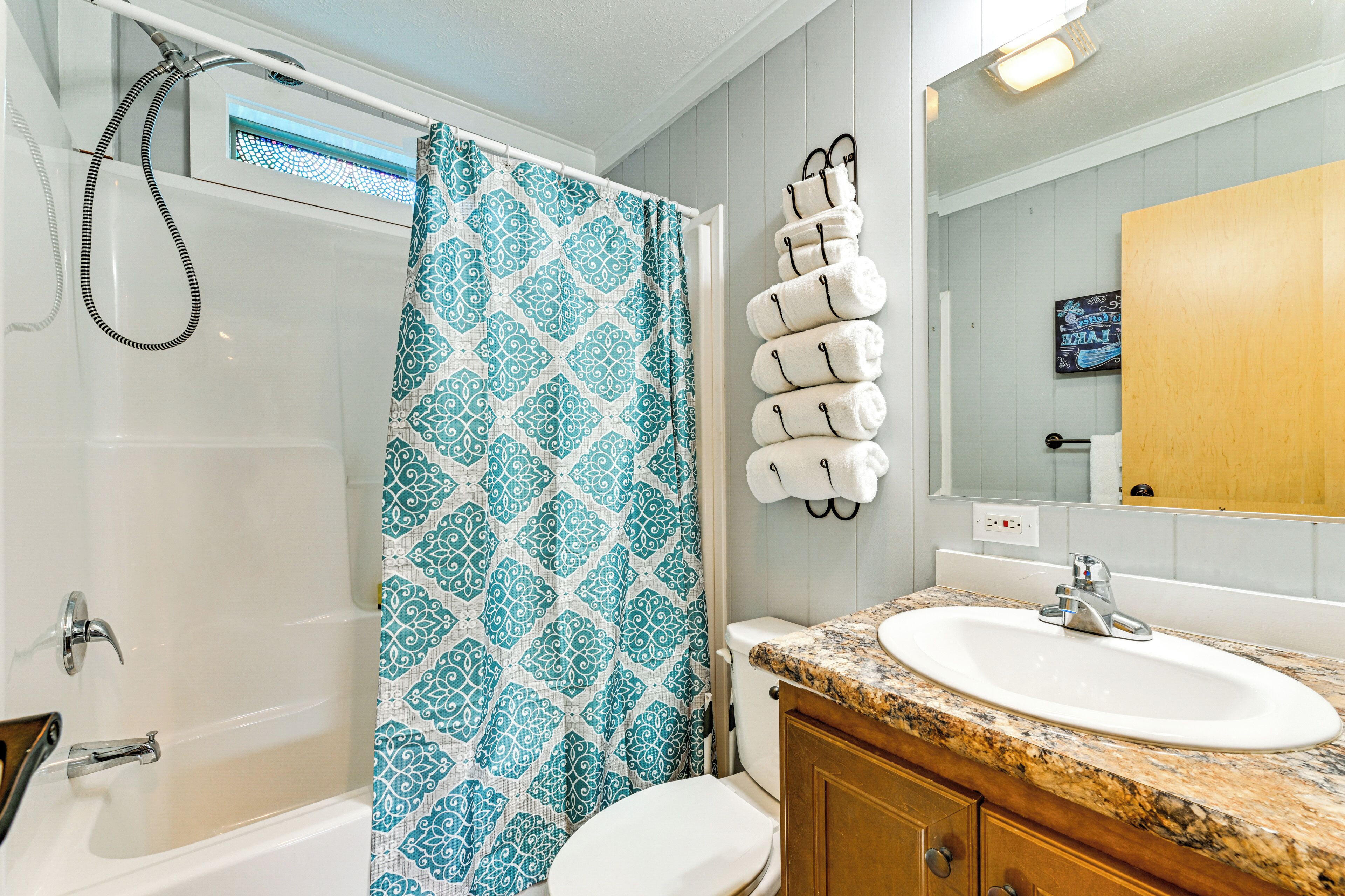 A bathroom with a shower, toilet, sink, and towel rack.