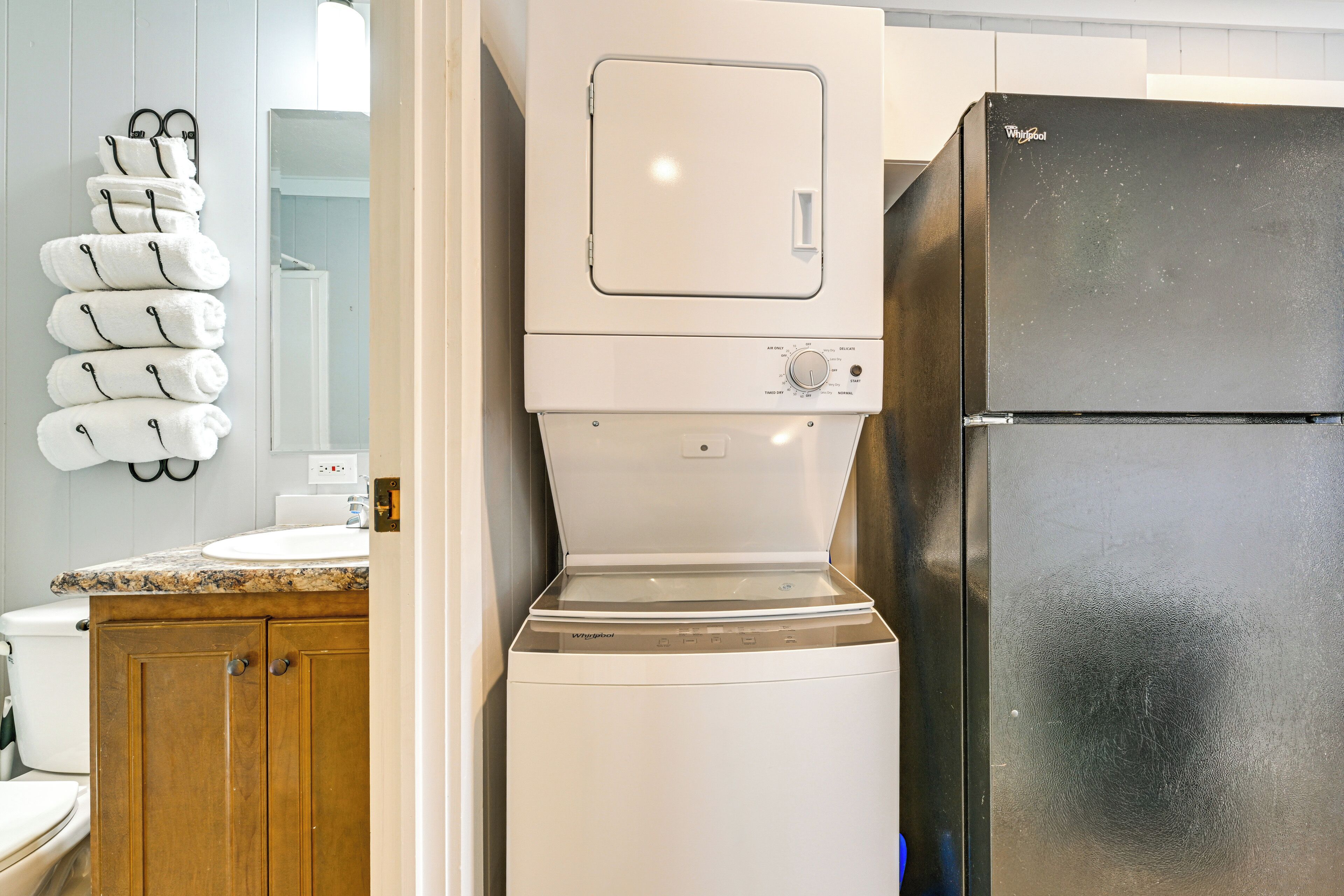 A compact kitchen with a built-in washer and dryer, wooden cabinets, and a stainless steel refrigerator.