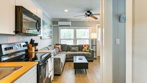 A compact kitchen with a stove, oven, and microwave. There is a wooden countertop, a sink, and a window with blinds. A ceiling fan is visible above the kitchen area. - Waterfront Living & Resort Perks! Lake Norman Stay (Sherrills Ford)