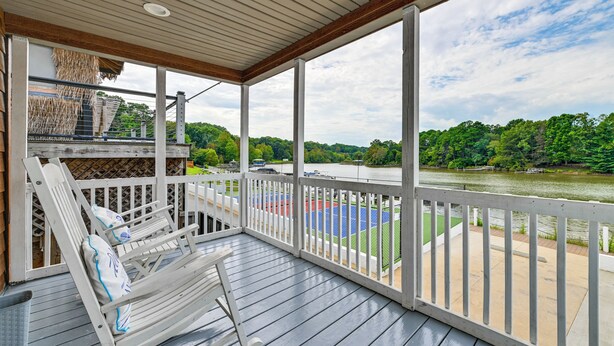 A covered outdoor deck with a view of a river and a tennis court. - Waterfront Living & Resort Perks! Lake Norman Stay (Sherrills Ford)