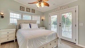 A bedroom with a large bed, a ceiling fan, and a door leading to a balcony. - Breathtaking Lake Views and Sunsets on Badin Lake! (New London)