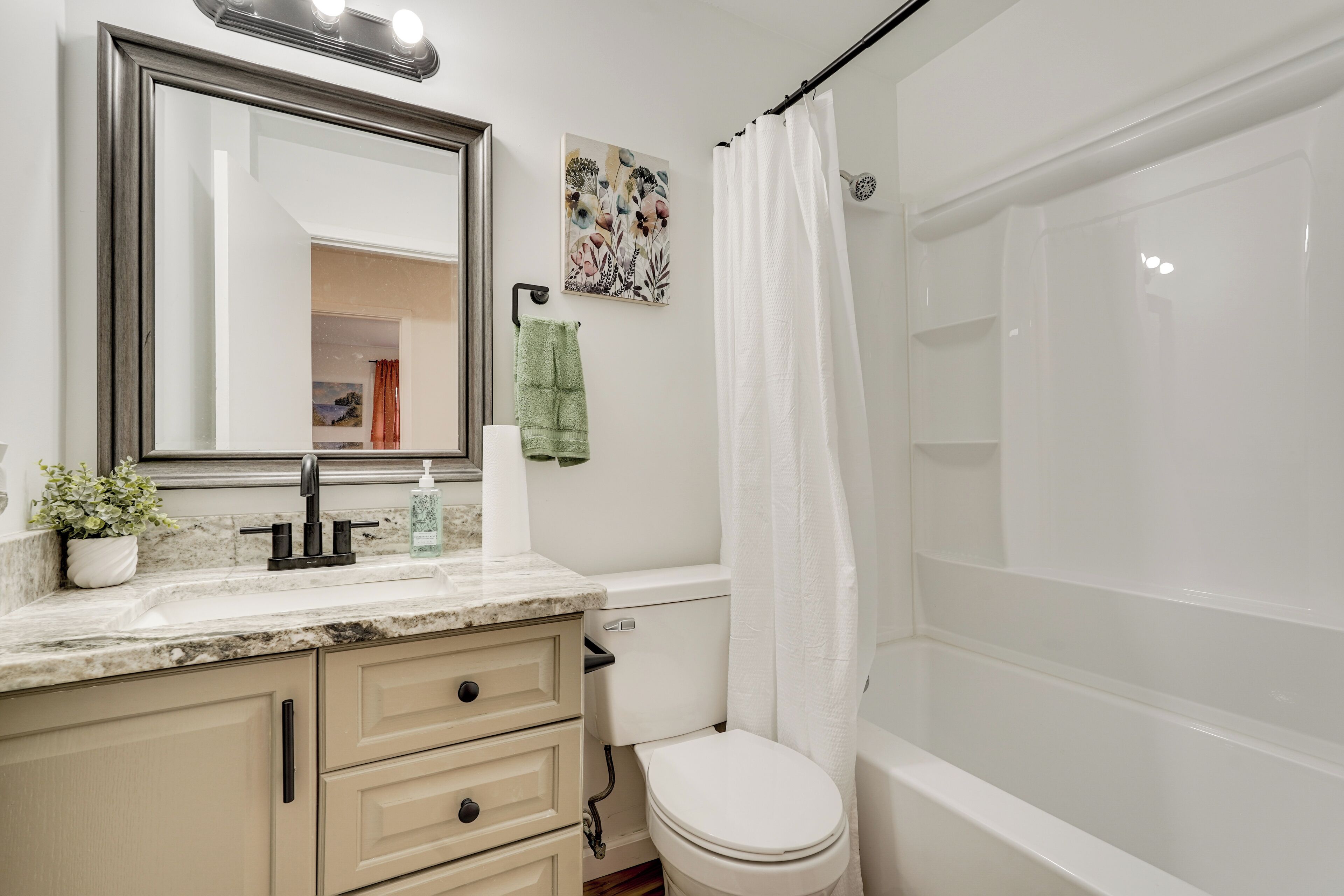 A bathroom with a sink, mirror, toilet, and bathtub.