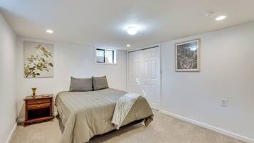 A bedroom with a bed, nightstand, and two windows.