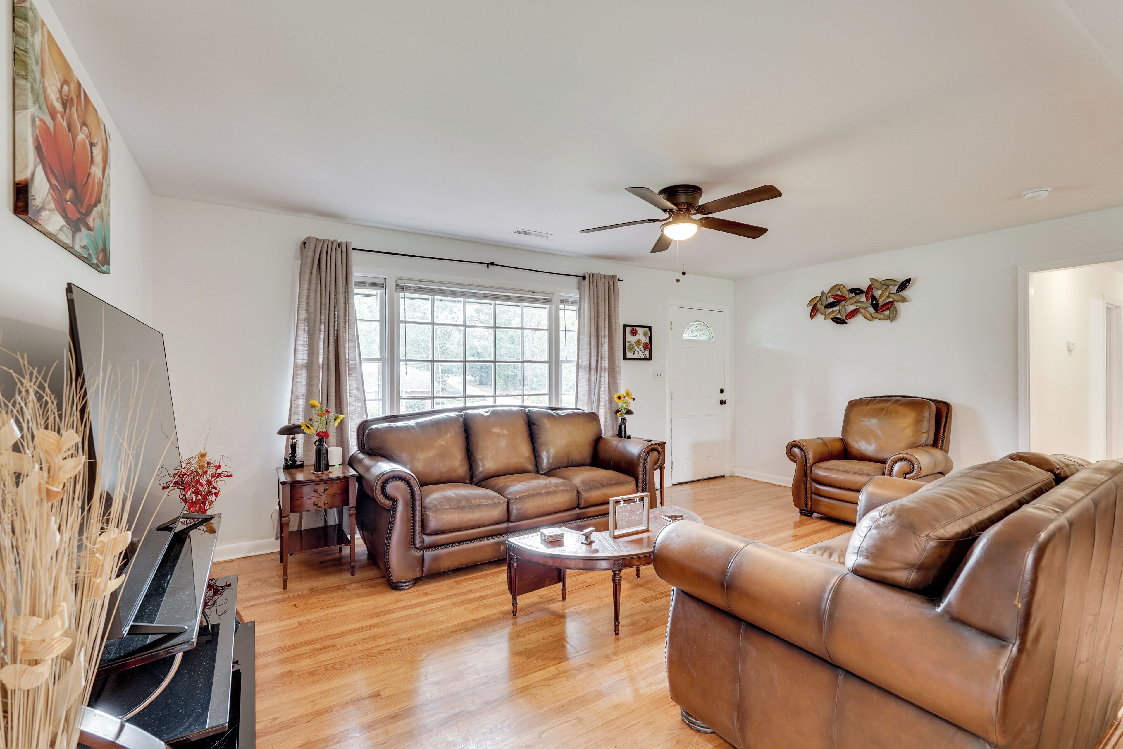 A spacious living room with a brown leather sofa, a coffee table, and a television.