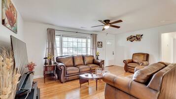 A spacious living room with a brown leather sofa, a coffee table, and a television.