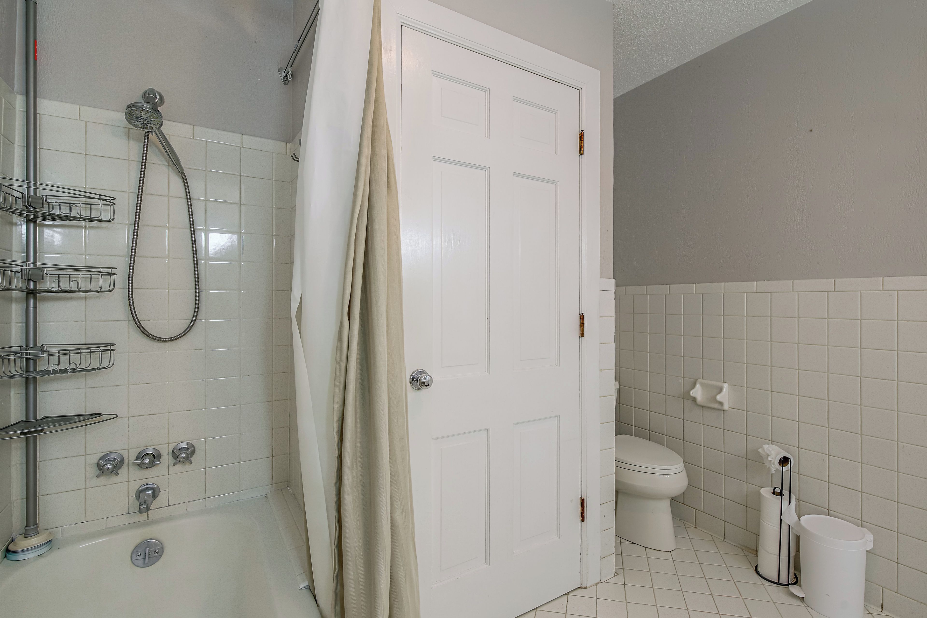 Un baño con ducha, inodoro y puerta.