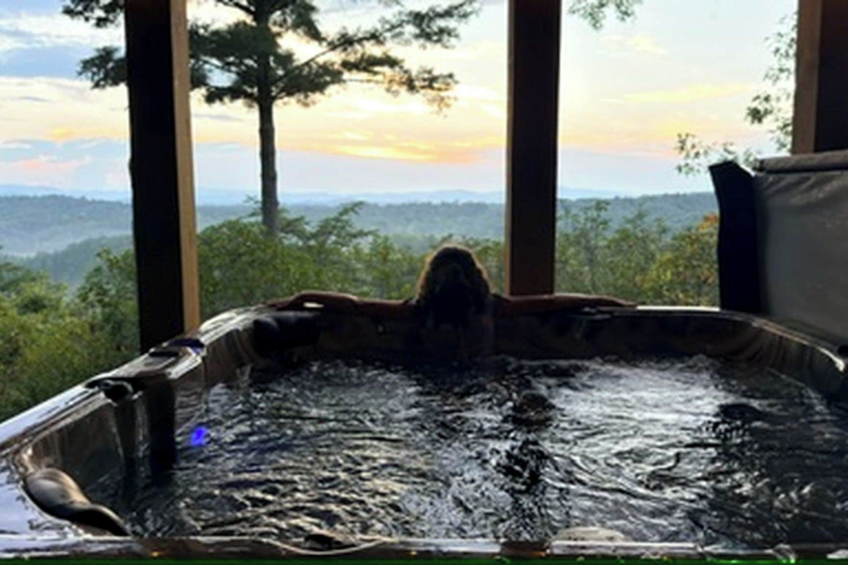 A hot tub with a view of a forest and mountains.