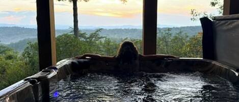 A hot tub with a view of a forest and mountains.