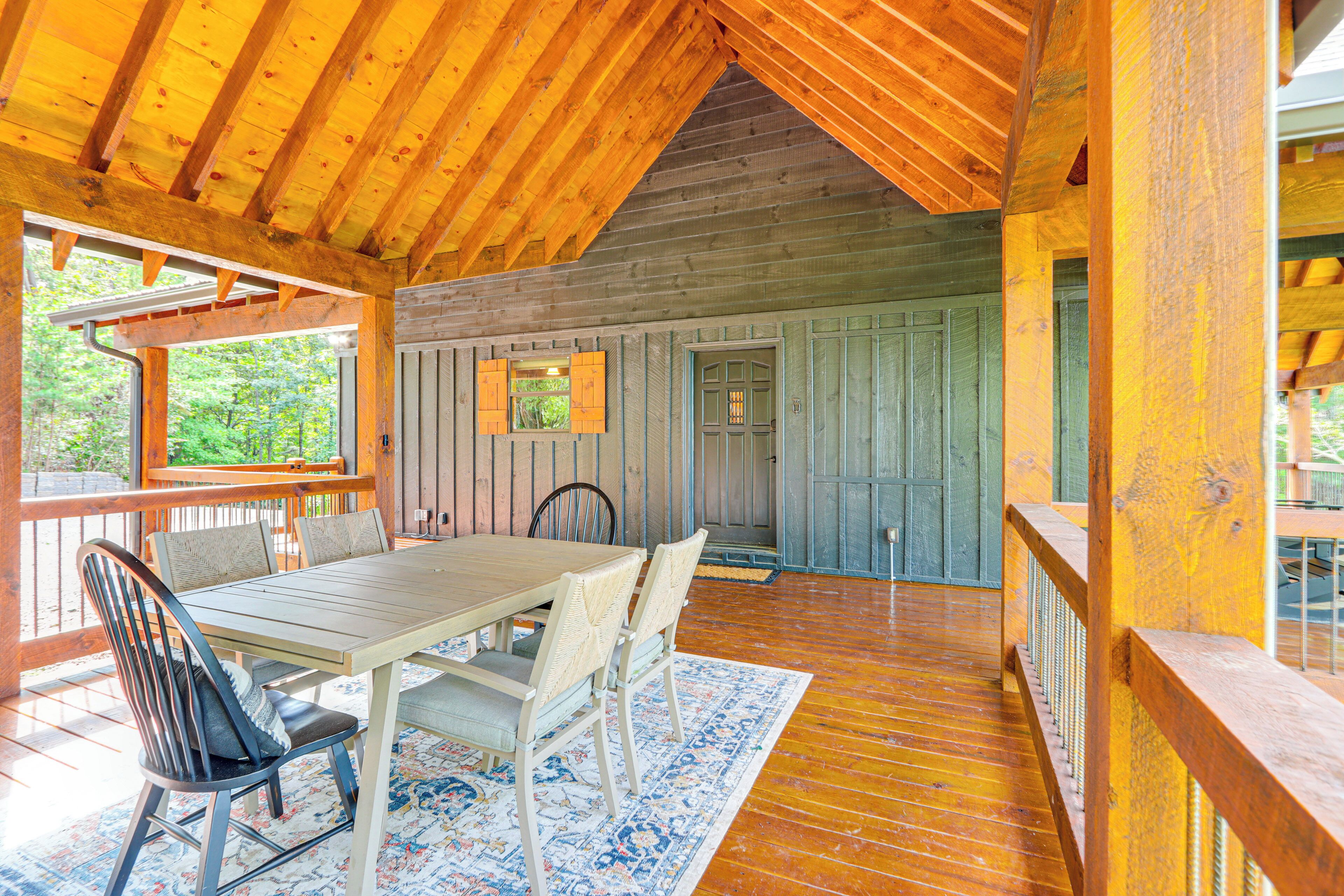 A wooden deck with a dining table and chairs, surrounded by wooden walls and a view of greenery.