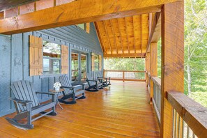 A wooden deck with Adirondack chairs and a table, overlooking a forested area. - Deck, Panoramic Views: Serene Mineral Bluff Cabin! (Mineral Bluff)