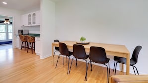 A modern kitchen with white cabinets, a wooden dining table, and black chairs. - Pet-friendly Minneapolis Home w/ Spacious Yard (Golden Valley)