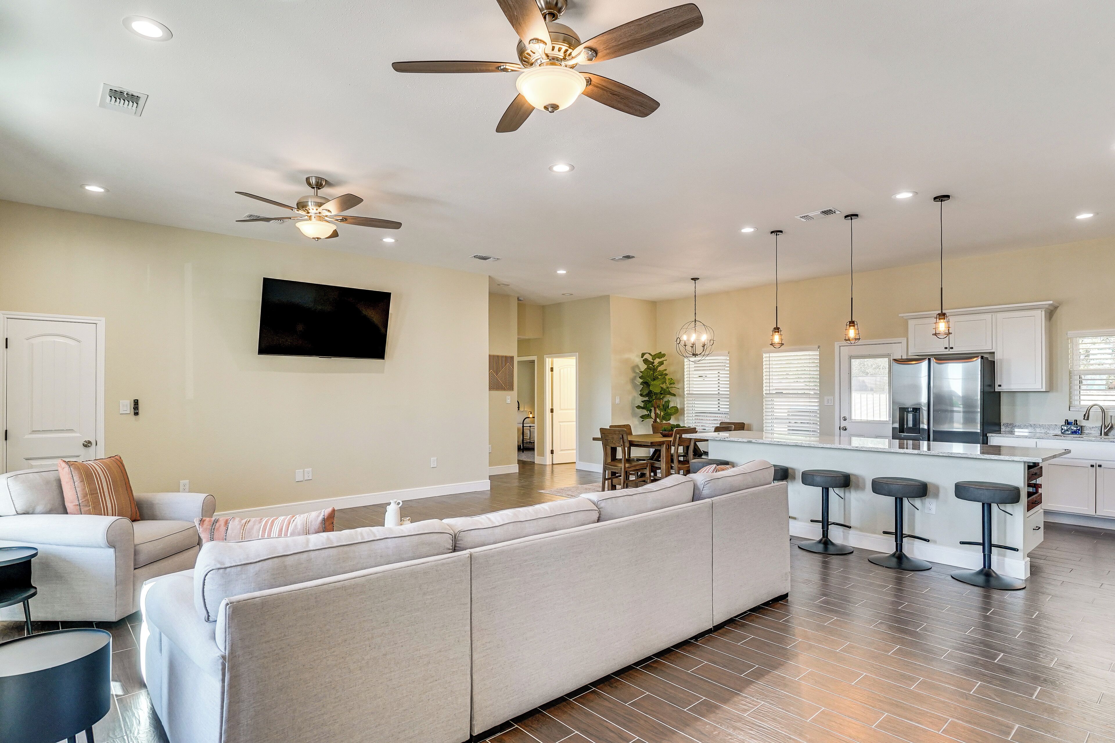 A spacious living room with a large sofa, a dining area, and a kitchen with a bar.