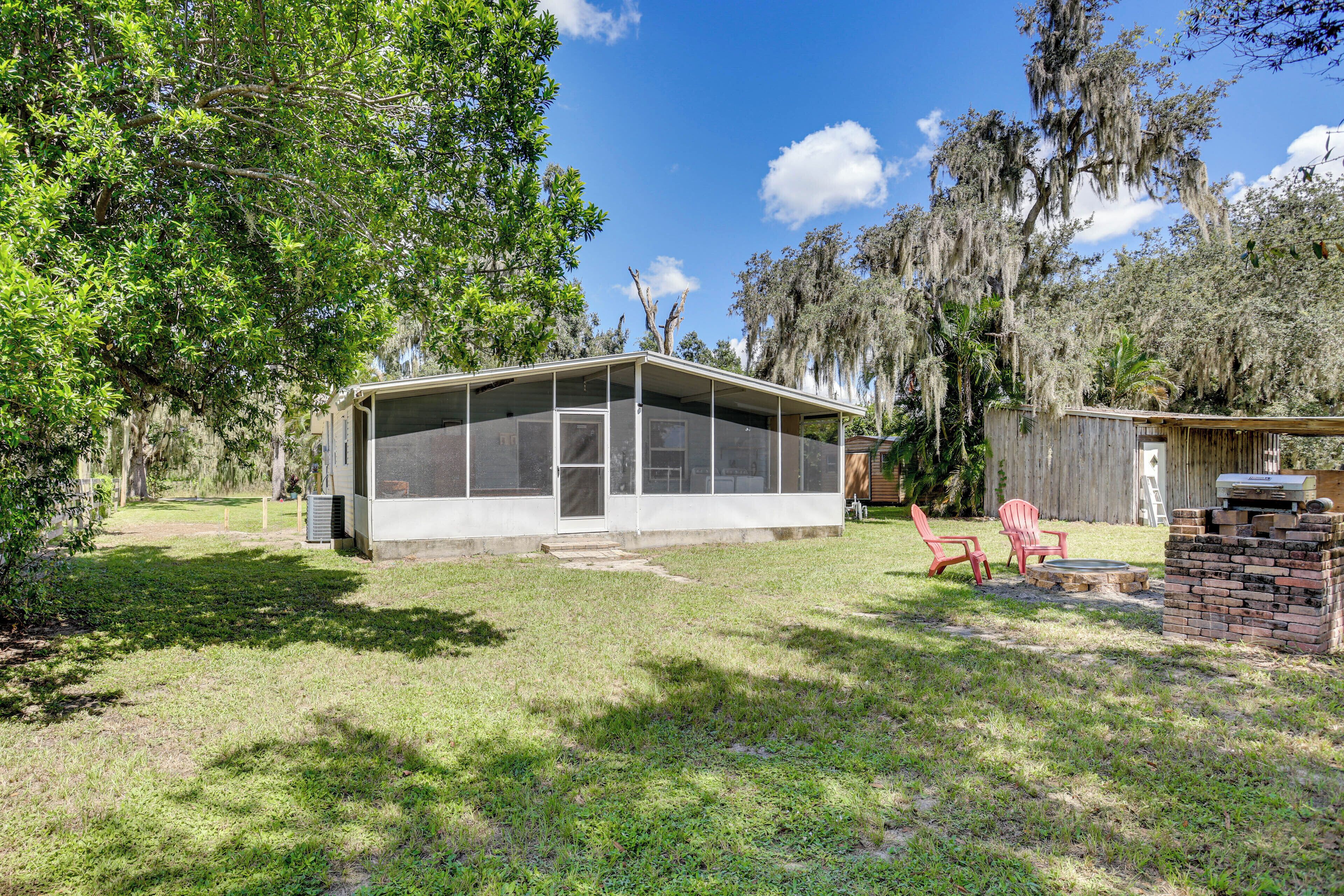 A single-story house with a screened porch, a small deck, and a brick barbecue area.