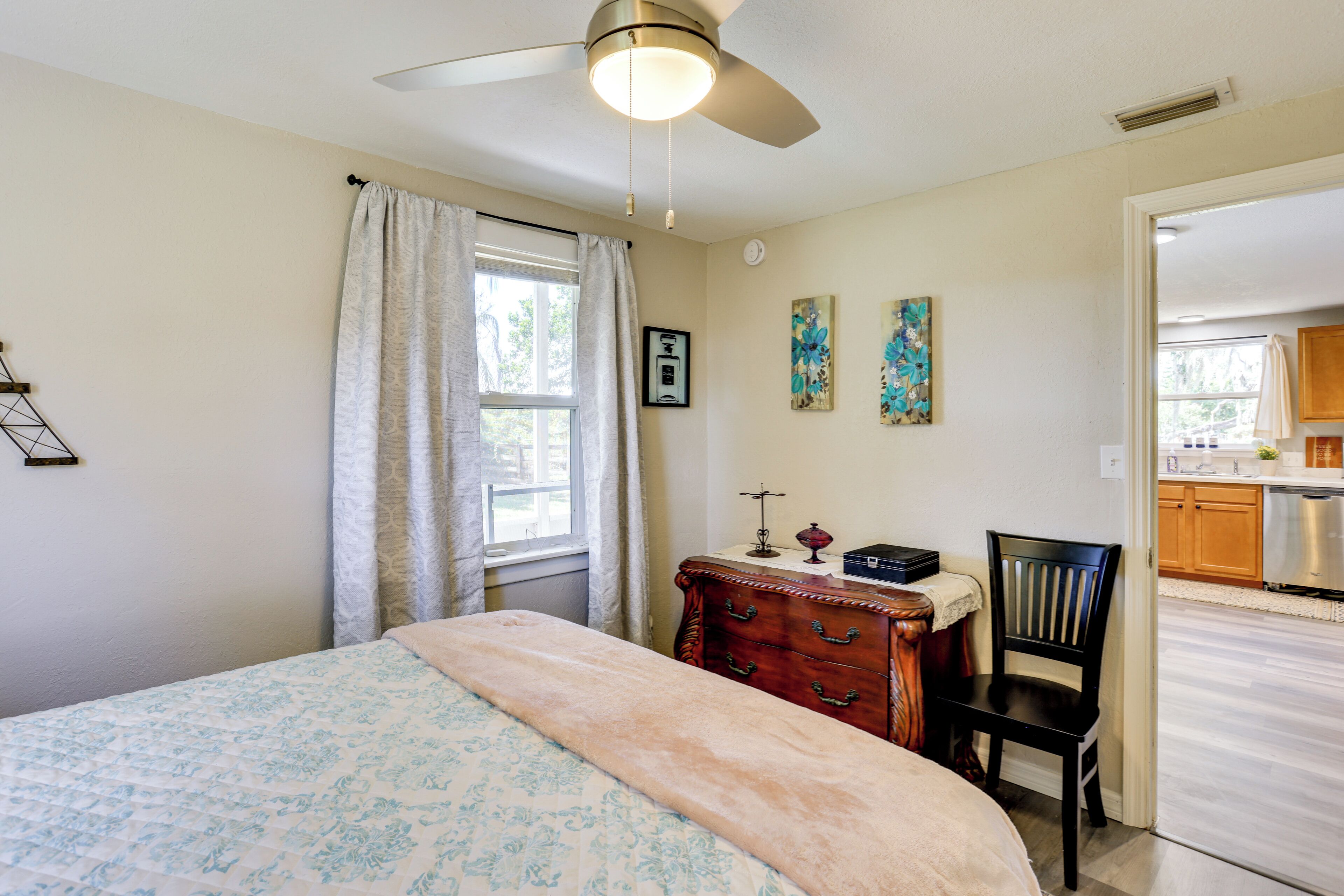 A bedroom with a bed, a dresser, a chair, and a ceiling fan.