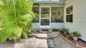 Une petite maison avec un porche, un chemin en briques et des plantes en pot.