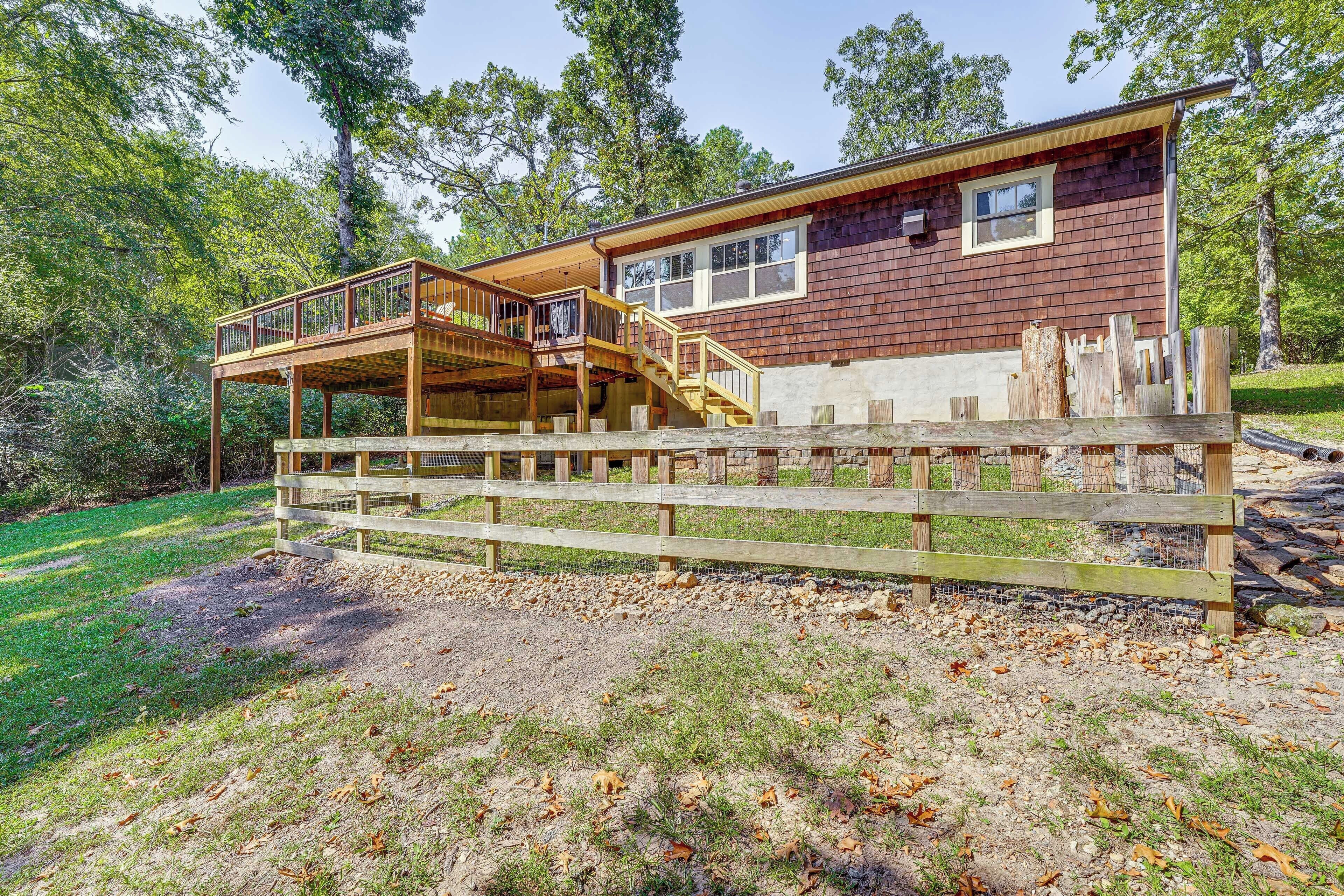 A two-story wooden cabin with a deck and a fenced yard.