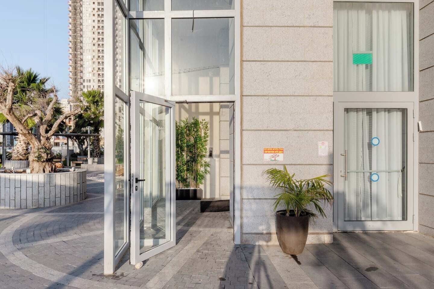 Une entrée moderne avec des portes en verre, une plante en pot et un panneau sur le mur.