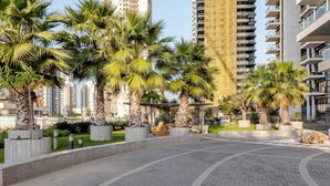 Una plaza pavimentada con palmeras y un edificio moderno al fondo.