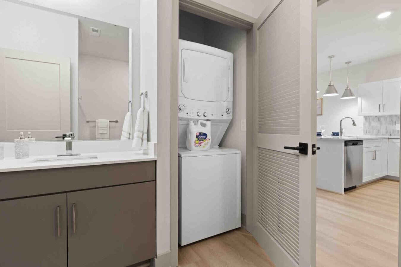 A modern kitchen with a built-in washing machine, a sink, and a countertop with a mirror.