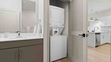 A modern kitchen with a built-in washing machine, a sink, and a countertop with a mirror.
