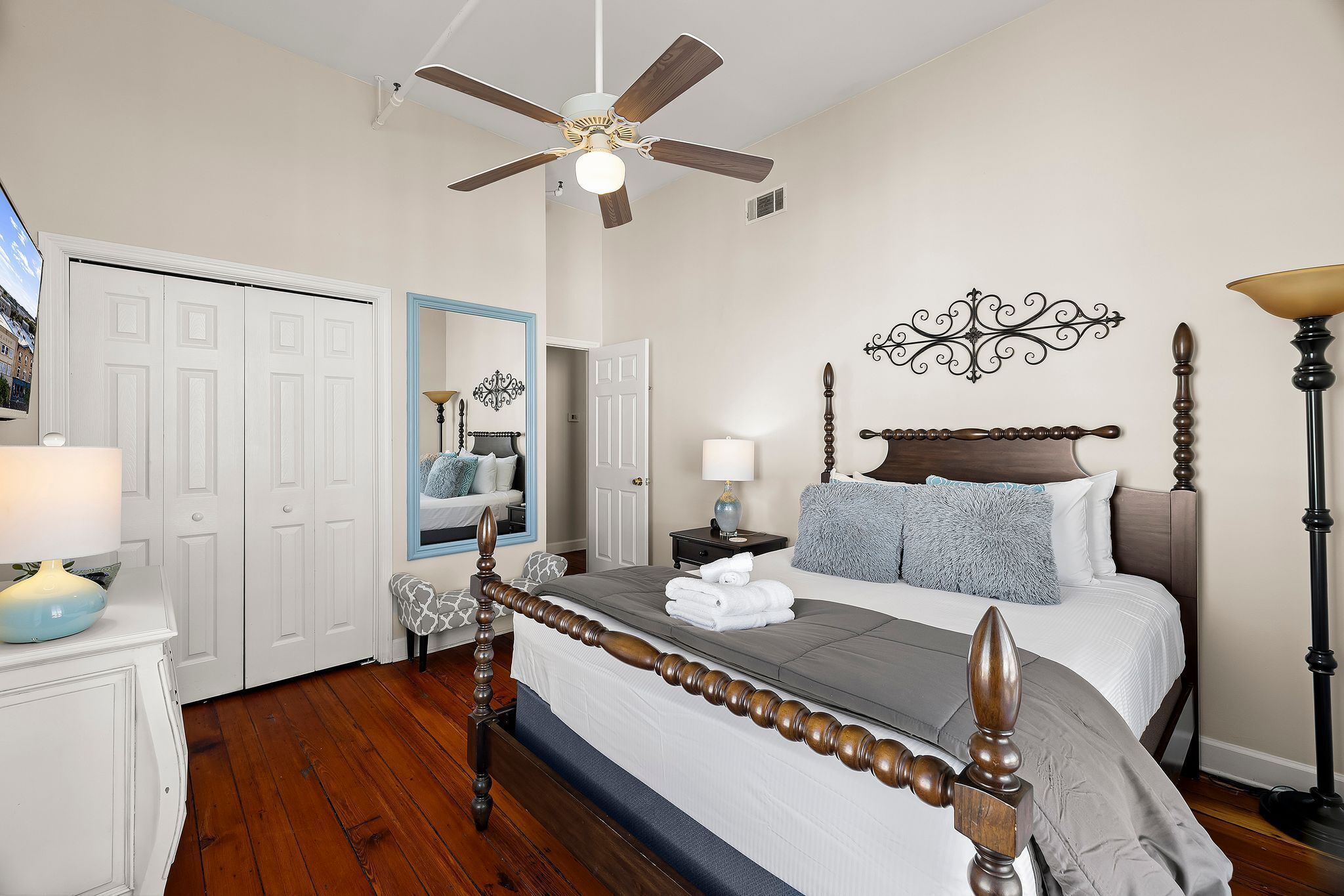 A bedroom with a bed, a ceiling fan, a nightstand, a lamp, and a wardrobe.