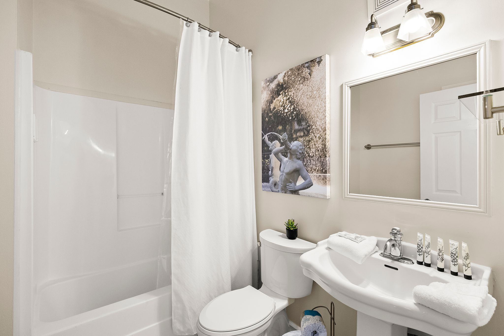 Un baño con bañera, inodoro, lavamanos y cortina de ducha.