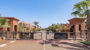 A gated entrance with palm trees and traditional architecture.