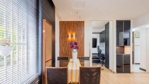 A modern living room with a dining area, a wooden accent wall, and a view of the kitchen.