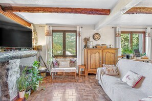 A cozy living room with a fireplace, a sofa, a television, and a wooden cabinet.
