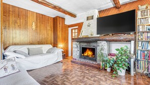 A cozy living room with a fireplace, a sofa, and a bookshelf.