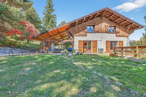 Ein Haus mit geneigtem Dach, einer überdachten Terrasse und einer Fassade aus Stein.