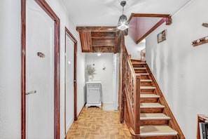 Un escalier en bois, avec un motif de plancher en chevrons, menant à un palier.