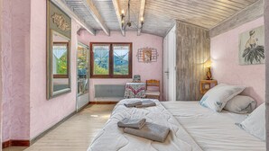 A bedroom with a bed, a chandelier, a window, and a door.