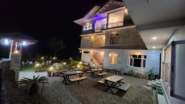 A multi-story building with outdoor seating and a staircase leading to the upper floor. - Destination Bir (Baijnath)