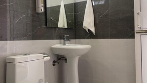 A modern bathroom with a toilet, sink, and mirror. - Destination Bir (Baijnath)