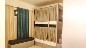 A room with bunk beds, a bench, and a window with curtains. - Destination Bir (Baijnath)