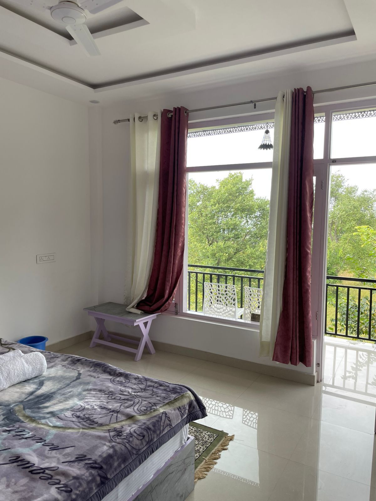 A bedroom with a bed, a small table, and a window with curtains.